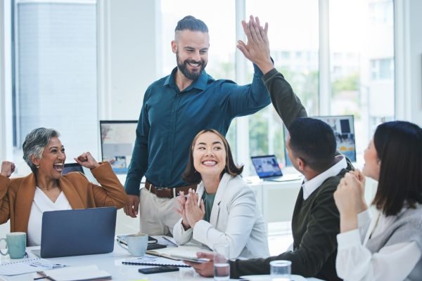 Equipe celebrando conquistas em uma reunião de negócios, mostrando entusiasmo e trabalho em equipe. Ambiente moderno e colaborativo.