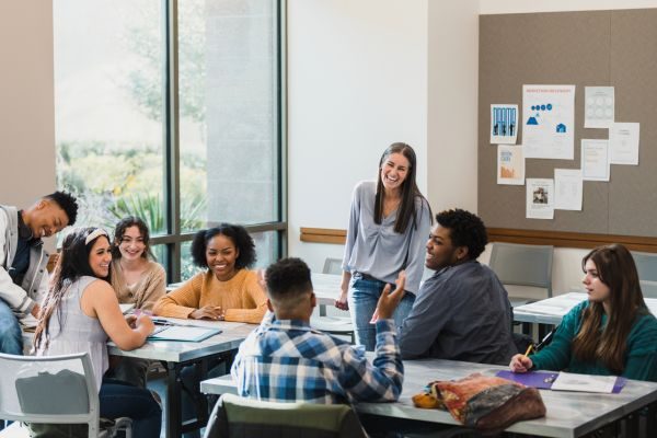 Grupo de jovens estudantes em ambiente colaborativo, discutindo e interagindo durante uma atividade em sala de aula, inspirando aprendizado e colaboração.