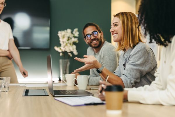 Grupo de profissionais felizes em uma reunião de trabalho, discutindo ideias e compartilhando experiências em um ambiente de escritório moderno.