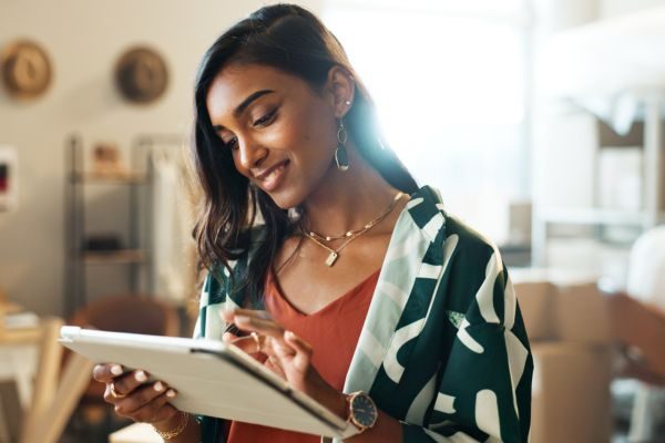 Mulher jovem usando um tablet em ambiente de trabalho, expressando satisfação e foco, simbolizando inovação e uso de tecnologia nos negócios