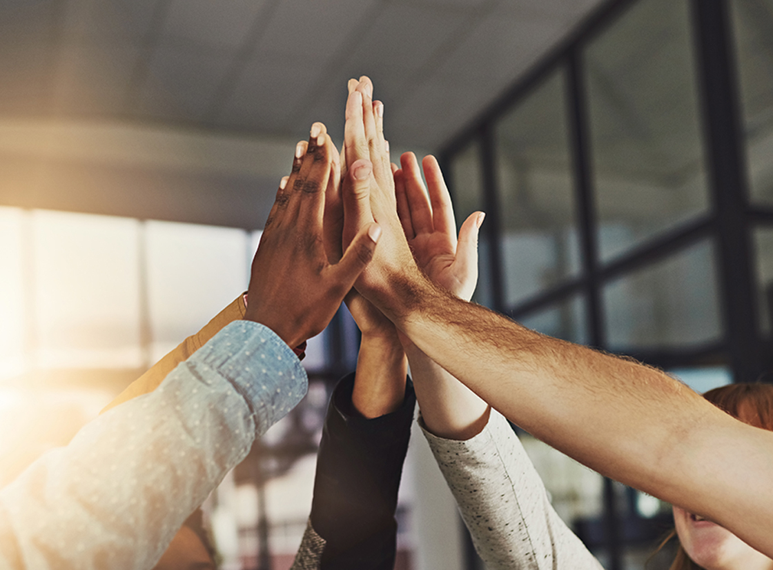 Diversas mãos unidas em um gesto de celebração e união, simbolizando trabalho em equipe, colaboração e sucesso.