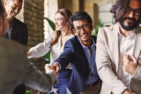 Grupo diversificado de profissionais realizando uma interação amigável, demonstrando habilidades de networking em um ambiente de negócios.